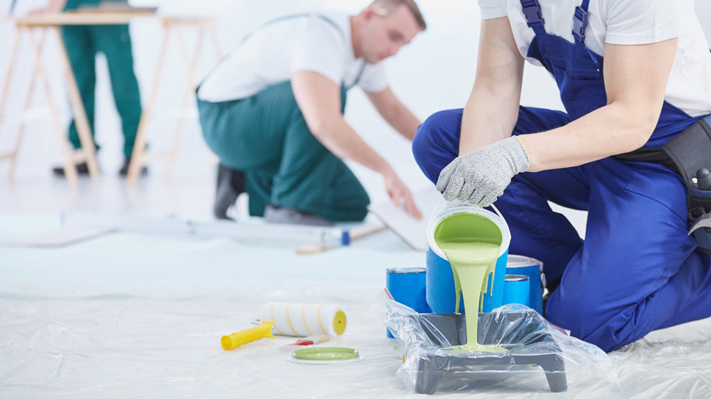 Professional interior construction worker pouring green color to paint